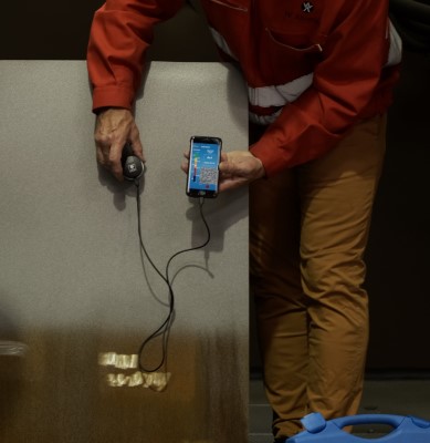 Muž (Technik) měří čistotu povrchu pomocí WA Clean iOS pomocí zařízení iphone